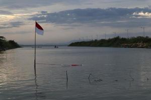 indonesische flagge, die am nachmittag vor dem hintergrund des sees und des himmels flattert foto