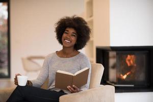 schwarze frau liest buch vor kamin foto