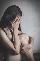 eine Frau, die allein und deprimiert sitzt. die depressionsfrau sitzt auf dem boden, missbraucht und menschen. sexueller missbrauch ist ein problem oder ein konzept für soziale fragen. häusliche Gewalt. foto