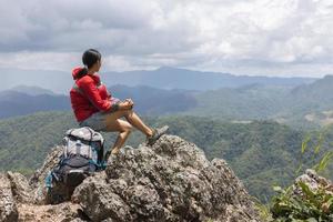 junge reisende frau mit stylischem rucksack, die sich auf den atemberaubenden blick auf die berge freut. Natur genießen, entspannen, genießen. foto