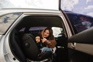 junge Mutter und Kind im Auto. Kindersitz auf Stuhl. Fahrsicherheitskonzept. foto