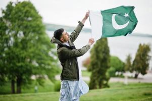 traditionelle kleidung indisches pakistanisches männliches porträt halten pakistan-flagge. foto