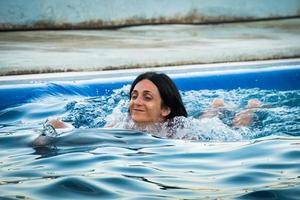 kaukasische frau schwimmt mit delphin im pool. batumi schwimmen mit delphinerlebniskonzept foto