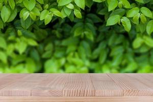 braune Holztischplatte auf bokeh abstraktem grünem Naturhintergrund - kann für die Montage oder Präsentation Ihrer Produkte verwendet werden foto
