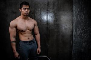 porträt des asiatischen mannes großer muskel im fitnessstudio, thailänder, training für gute gesunde, körpergewichtstraining, fitness im fitnessstudio-konzept foto