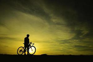 Silhouette eines gutaussehenden Mannes, der bei Sonnenuntergang Fahrrad fährt, Sportmannkonzept foto