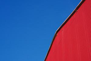 Urbaner abstrakter Minimalismus. rote gebäudefassade mit metallverkleidung am blauen himmel, niemand foto