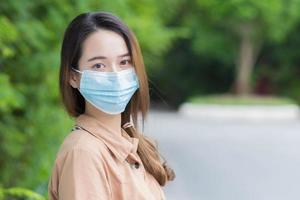coronavirus und luftverschmutzung pm2.5 konzept. Junge schöne asiatische Studentin trägt eine Maske, um das Coronavirus zu verhindern. beim Gehen nach Hause