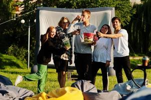 junge multiethnische gruppe von menschen, die filme im poof im open-air-kino ansehen. foto