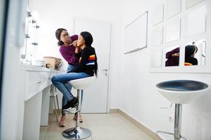 Afroamerikanerin beim Schminken durch Make-up-Künstlerin im Schönheitssalon. foto