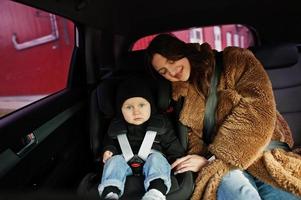 junge Mutter und Kind im Auto. Kindersitz auf Stuhl. Fahrsicherheitskonzept. foto