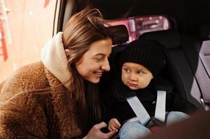 junge Mutter und Kind im Auto. Kindersitz auf Stuhl. Fahrsicherheitskonzept. foto