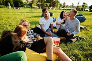 junge multiethnische gruppe von menschen, die filme im poof im open-air-kino ansehen. foto