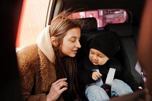 junge Mutter und Kind im Auto. Kindersitz auf Stuhl. Fahrsicherheitskonzept. foto