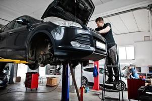 Thema Autoreparatur und -wartung. Mechaniker in Uniform, der im Autoservice arbeitet. foto