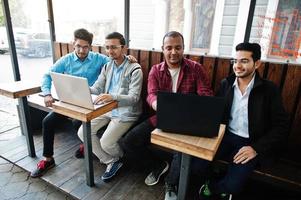 Gruppe von vier indischen jugendlich männlichen Studenten. Klassenkameraden verbringen Zeit miteinander und arbeiten an Laptops. foto