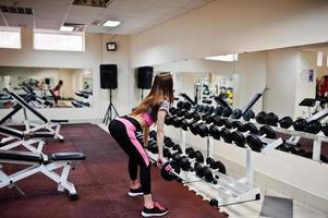 junges brünettes sexy schlankes mädchen, das im fitnessstudio trainiert. foto