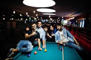 Eine Gruppe stilvoller asiatischer Freunde trägt Jeans und spielt Billard an der Bar. foto