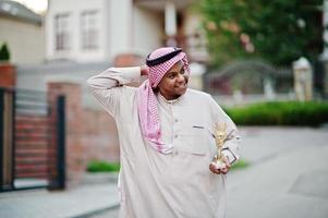 arabischer geschäftsmann aus dem nahen osten posierte auf der straße mit einer goldenen tasse an den händen. foto