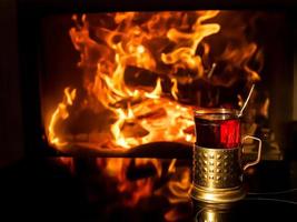 Glas Tee im Getränkehalter am Kamin foto