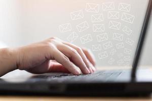Frauenhand tippen auf Tastaturkonzept zum Empfangen oder Senden von E-Mail-Symbolen auf dem Schreibtisch mit Laptop foto