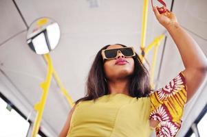 junge stilvolle afroamerikanerin in moderner sonnenbrille, die in einem bus fährt. foto