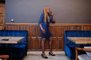 Porträt einer schönen jungen afrikanischen Geschäftsfrau mit Dreadlocks, blauer Bluse und Rock, posiert im Café. foto