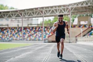 afroamerikanischer männlicher athlet in sportbekleidung, der allein auf einer laufbahn im stadion rennt. foto