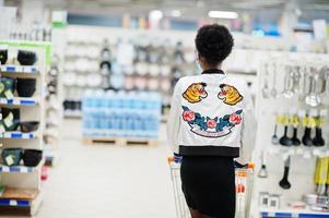 afrikanische frau mit medizinischer einwegmaske und handschuhen, die während des ausbruchs der coronavirus-pandemie im supermarkt einkaufen. epidemische Zeit. foto