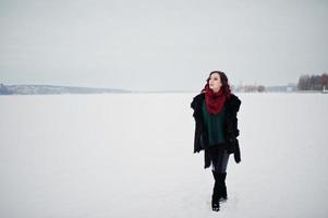 brünettes mädchen in grünem pullover und rotem schal im freien zugefrorenen see am abend wintertag. foto