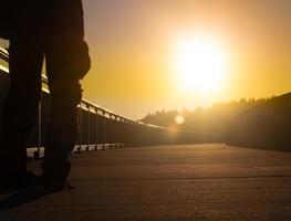 Mann, der bei Sonnenaufgang über eine Brücke geht foto