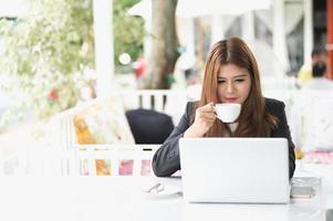 asiatische Frau im Café mit Laptop und Kaffee, Geschäftskonzept foto