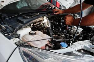 Thema Autoreparatur und -wartung. mechaniker in uniform, der im autoservice arbeitet und den motor überprüft. foto