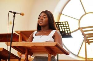 Afroamerikanerin, die in der Kirche betet. Gläubige meditieren in der Kathedrale und spirituelle Gebetszeit. Afro-Mädchen, das Gott in Refrains singt und verherrlicht. foto