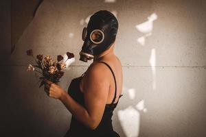 Frau mit Gasmaske und Blumenstrauß foto