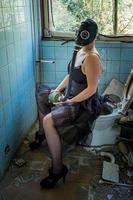 Frau mit Gasmaske auf einer Toilette foto