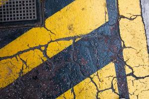gelbe streifen auf dem grungigen rissigen asphalt, muster und textur, bunter hintergrund, strukturierte oberfläche foto