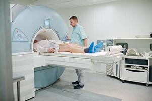 Der männliche Arzt schaltet das Magnetresonanztomographiegerät mit dem Patienten im Inneren ein. foto