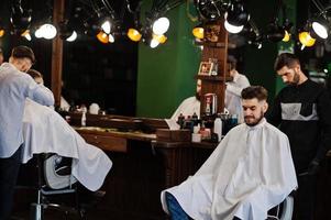 hübscher bärtiger mann im friseursalon, friseur bei der arbeit. foto