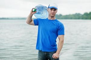 Lieferbote mit Wasserflasche auf der Schulter. foto