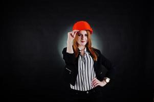 Ingenieurfrau in orangefarbenem Schutzhelm auf schwarzem Studiohintergrund. foto