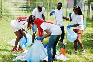 gruppe glücklicher afrikanischer freiwilliger mit müllsäcken, die bereich im park reinigen. afrika-freiwilligenarbeit, wohltätigkeit, menschen und ökologiekonzept. foto