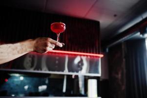 alkoholischer roter Cocktail mit Minze in der Hand des Barkeepers. foto