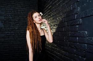 Studio-Shooting von Mädchen in Schwarz mit Dreads auf Backsteinhintergrund. foto