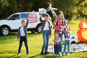 amerikanische familie verbringt zeit zusammen. mit usa-flaggen gegen großes suv-auto im freien. foto