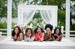 Gruppe von fünf afroamerikanischen Mädchen, die sich in der wunderschönen Cabana am Pool neben dem Luxusresort entspannen. foto