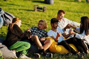 junge multiethnische gruppe von menschen, die filme im poof im open-air-kino ansehen. foto