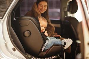 junge Mutter und Kind im Auto. Kindersitz auf Stuhl. Fahrsicherheitskonzept. foto