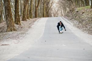 arabischer Streetstyle-Mann in Brille mit Longboard Longboarding die Straße hinunter. foto