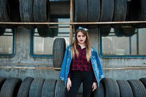 Junges Hipster-Mädchen in Jeansjacke und Kopftuch in der Reifenmontagezone. foto